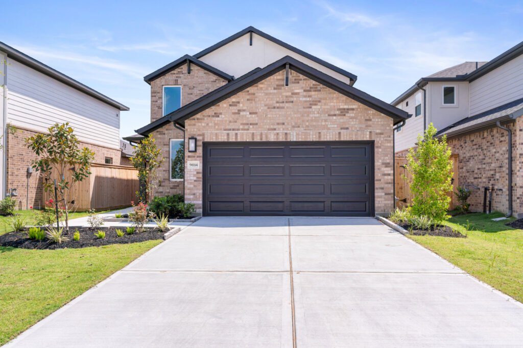 Brick home with dark garage door and wide driveway